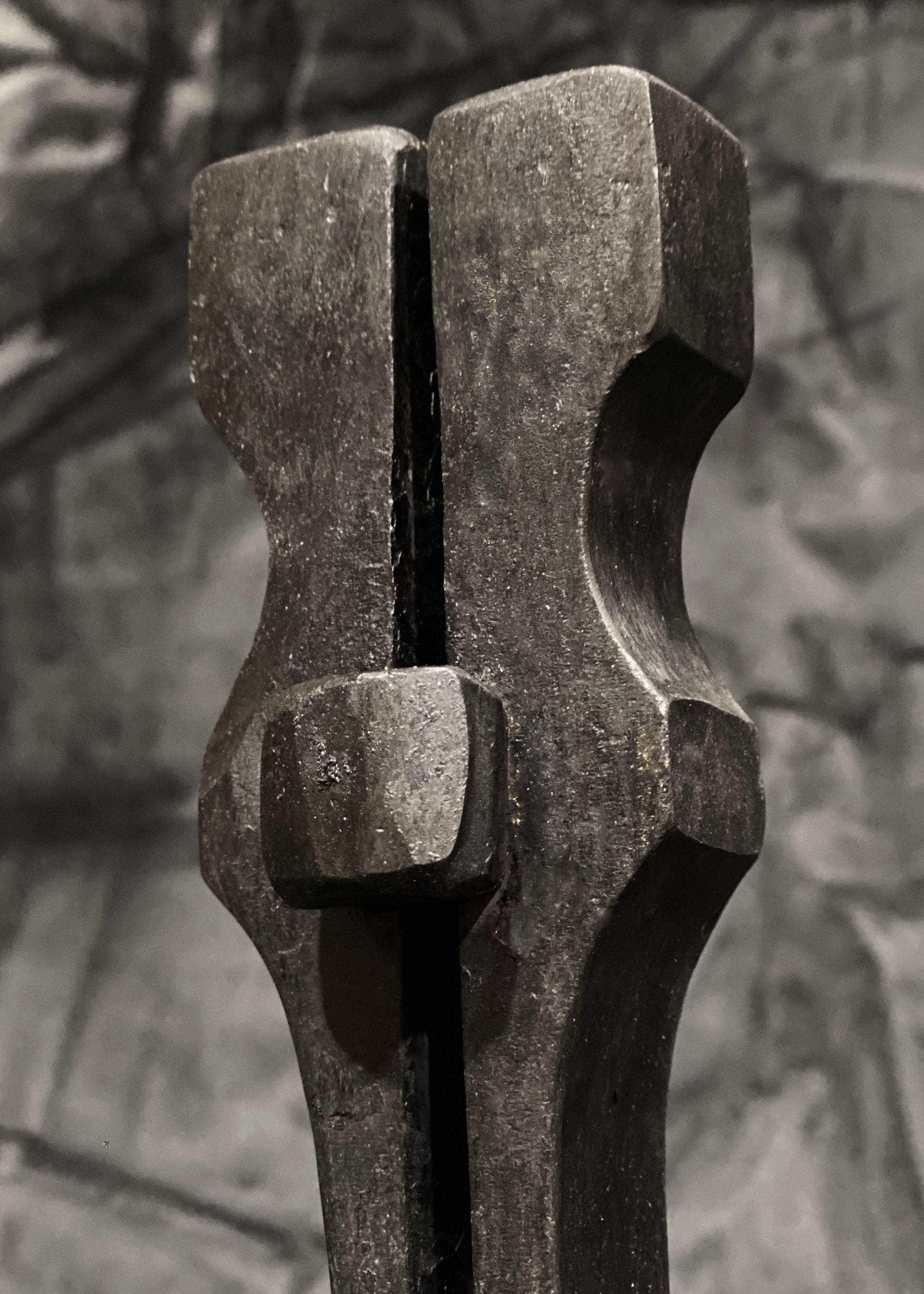 A forged sculpture of two pillars that rise up and join at the top, with a textured surface.
